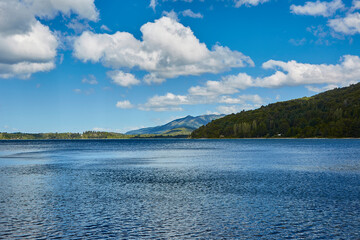 Lake between mountains and vegetation in argentine patagonia. Light blue sky with fluffy clouds.
