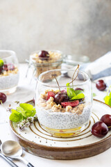 Healthy menu concept. Home made granola breakfast. Glass of parfait made of granola, berries cherry, yogurt with chia seeds on rustic table. Copy space.