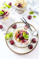 Healthy menu concept. Home made granola breakfast. Glass of parfait made of granola, berries cherry, yogurt with chia seeds on rustic table. View from above.