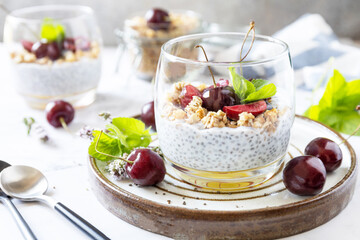 Healthy menu concept. Home made granola breakfast. Glass of parfait made of granola, berries cherry, yogurt with chia seeds on rustic table.
