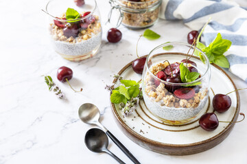 Healthy menu concept. Home made granola breakfast. Glass of parfait made of granola, berries cherry, yogurt with chia seeds on rustic table. Copy space.
