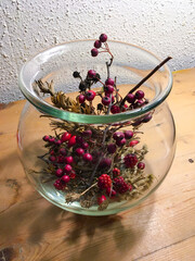 Brombeeren, Ilex, Hagebutte und Gräser in einer Glasvase herbstlich dekoriert 