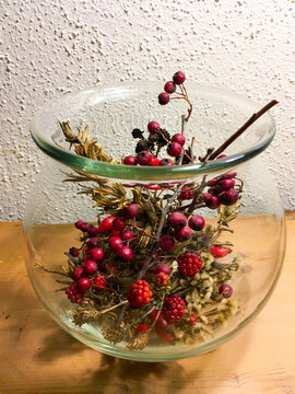 Brombeeren, Ilex, Hagebutte und Gr&auml;ser in einer Glasvase herbstlich dekoriert 