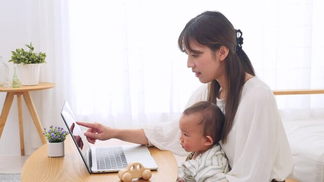 赤ちゃんとノートパソコンを見る母親
