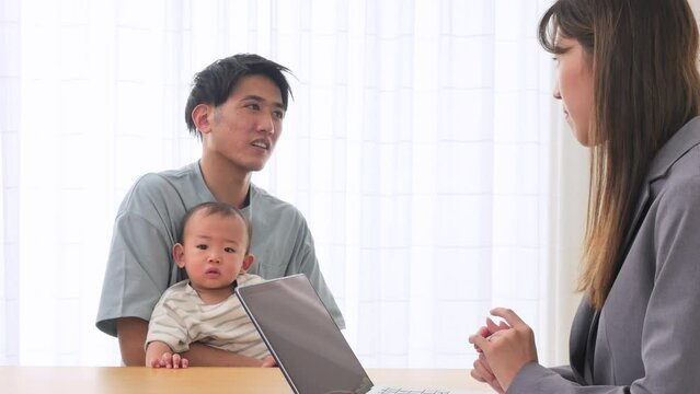 リビングで赤ちゃんの父親と話す女性外交員