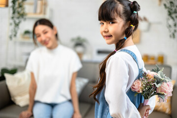 Attractive beautiful asian  mum sitting on sofa . daughter give gift box and flower in family moment.Women's or Mother's day or birthday, sitting on sofa.