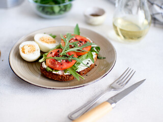 Balanced breakfast of eggs, sandwich with cheese, tomatoes, green and hot coffee on light background. Diet food.