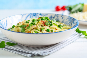 Spaghetti with zucchini and green peas close up.