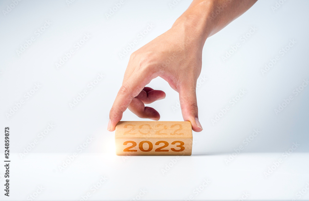 Poster close up hand flipping the 2022 to 2023 year numbers calendar on wooden cube blocks for preparation 