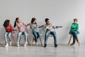 Diverse Classmates Children Laughing Pointing Finger At Victimized Schoolboy Indoor