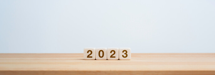 2023 Happy New year background banner. Two thousand Twenty-Three year numbers on wooden cube blocks isolated on white background with copy space. Welcome, Merry Christmas, and Happy New Year in 2023.