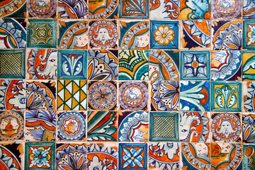 Photo of a mosaic wall of an old building. Photo tiles. Mosaic, wall tiles, ceramics, tiles, abstract motif. Multicolored wall decor. Texture of ceramic tiles in oriental style. Selective focus.