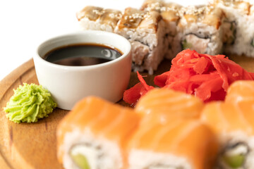Cup of soy sauce on plate with salmon sushi rolls