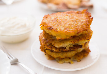 Potato pancakes with sour cream on white plate