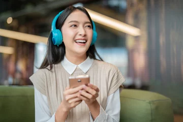 Foto op Plexiglas relax joyful casual asian female adult woman casual cloth enjoy listening music from streaming online playing music playlist application on smartphone via earphone  on sofa couch at co working space © whyframeshot