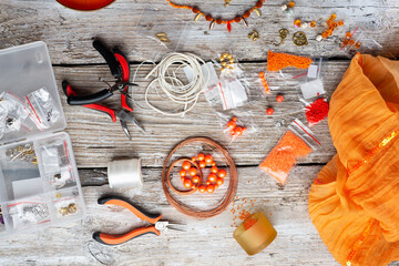 orange set for handmade jewelry with necklace  around white old style wooden background. close up