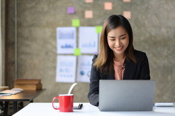 Attractive young Asian business woman in office working on laptop.