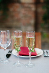 Two glasses of white wine, decorated with sprigs of greens.