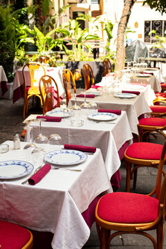 Served restaurant tables and chairs outside in the central street of Sanremo, Italy. Summer. No people. Vertical image.