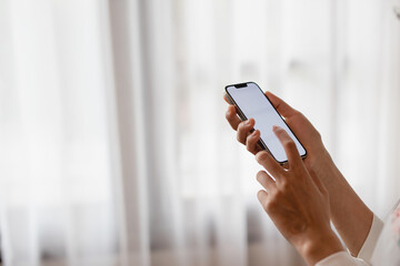 Close-up of a woman's hand using a mobile phone at home. Search ideas or social networks.