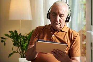 Frowning Man Watching Video on Tablet