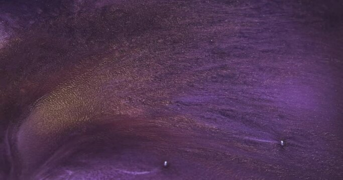 Shining golden sparkles spread in lilac liquid, abstract background. Purple paint moving, flowing liquid. Shining violet moving. Slow motion art. 4k vertical video backdrop. Watercolor paints backdrop