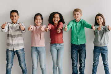 Happy Multiethnic Kids Gesturing Thumbs Up Posing Standing Indoor