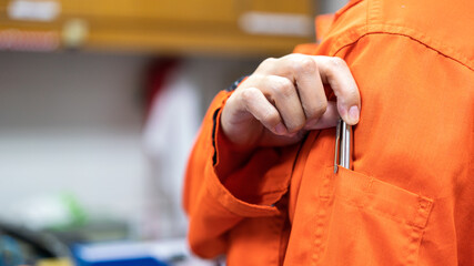 Action of a manager is picking a luxury ballpoint pen which is tucked at arm part of coveralls working uniform. Business person working scene, close-up and selective focus.