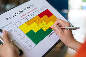 Action of manager is rating on project investment plan risk assessment matrix, decision to reduce risk from high (A) to medium level (B). Industrial and business working concept, selective focus. - obrazy, fototapety, plakaty