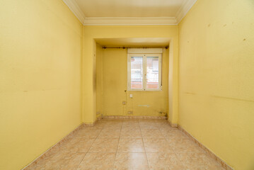 Empty room with light stoneware floor, dirty yellow painted walls, aluminum window with views and plaster border on the ceilings