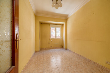 Empty room with light stoneware floor, dirty yellow painted walls, aluminum window with view and plaster trim on ceilings