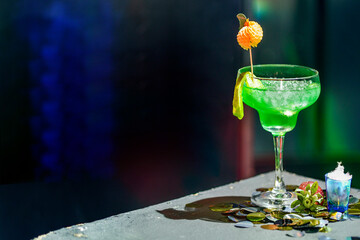 Green festive drink glass with lots of ice, lime and a ripe strawberry