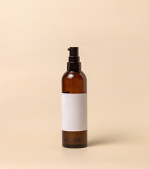 Cosmetic One pump glass bottle with blank label on light beige, packaging Mockup