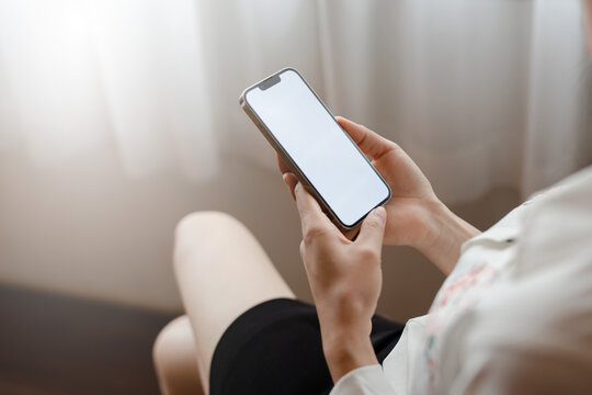 Close-up of a woman's hand holding a cell phone with a dummy copy space screen for your ad content. Asian girl watching web video on mobile phone during vacation.