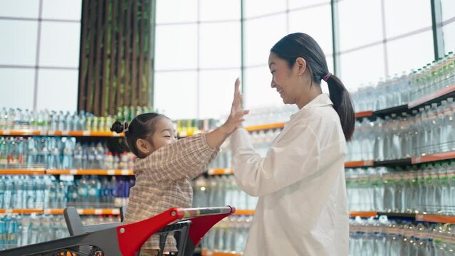 Happy mother plays patty-cake with daughter in supermarket