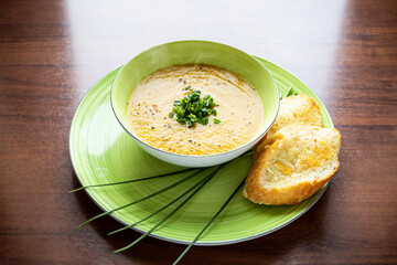 zupa krem z kabaczka i marchewki ze szczypiorkiem i grzankami na zielonym talerzu - 524870420