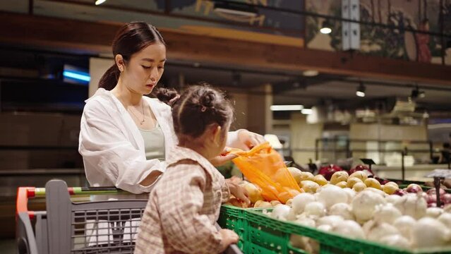 Mother and daughter choose together potato in supermarket