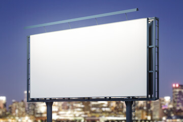 Fototapeta premium Blank white billboard on city buildings background at night, perspective view. Mockup, advertising concept