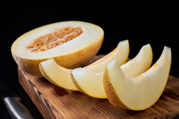 Close-up of melon slices and melon halves with a knife on a wooden board