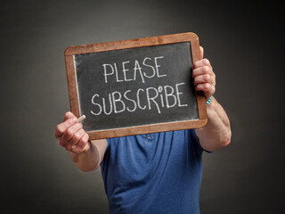 please subscribe, slate blackboard sign in chalk held by a man, social media and communication concept