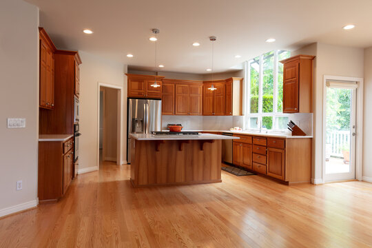 Remodeled kitchen in home with island plus built in stove top, pendant lights, oak hardwood floors and stainless steel appliances