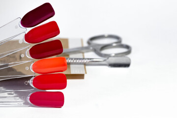 Samples of red gel polish on the background of blurred tools for professional manicure or pedicure with space for text.