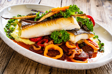 Fish dish - fried halibut with potato puree, fried pepper and chorizo on wooden table
