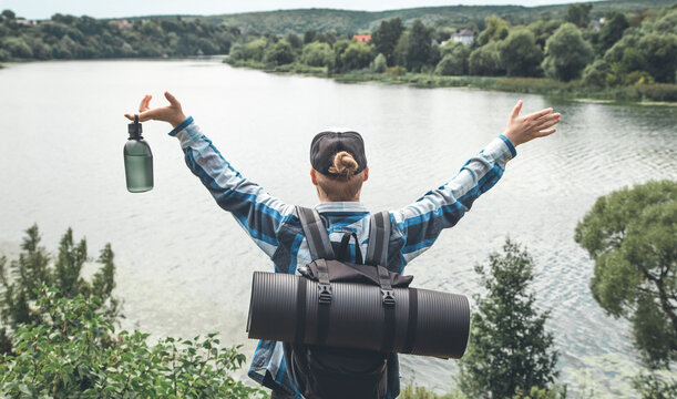 Male traveler with backpack and karimat in nature, back view.
