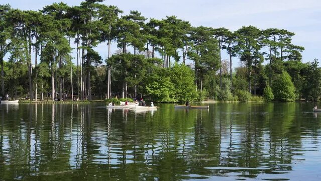 Parisians boating on the lower lake in the Bois de Boulogne on a summer week-end day - Paris, France