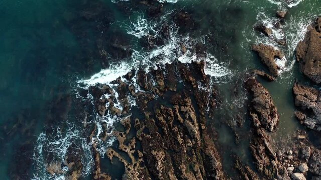 Aerial view of the ocean crashing into the rocks on the coast of swansea, mumbles UK. clear blue coast stunning views.