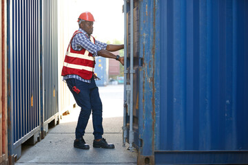 African factory worker or foreman opening the container door in warehouse storage