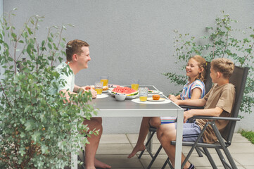 Happy dad with teen children having brunch outdoors