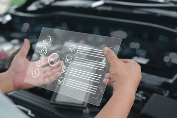 Car business concept and technology on virtual screen, Serviceman hold smart checklist screen check item list of car mileage for maintenance and service with the engine room in the background - obrazy, fototapety, plakaty