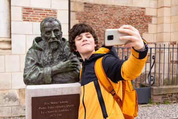 Teenager boy taking a selfie with a monument, making funny content for social media. Travelling student, sightseeing. - obrazy, fototapety, plakaty